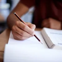 close-up of a hand holding a pencil to paper