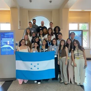 a group of medical students hold a flag from honduras inside the college they're visiting