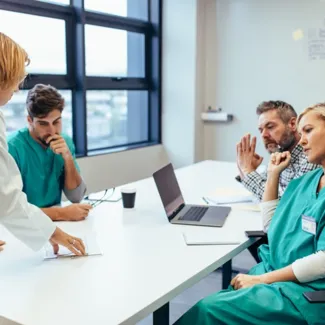 a group of people in scrubs sitting at a table, looking at a paper