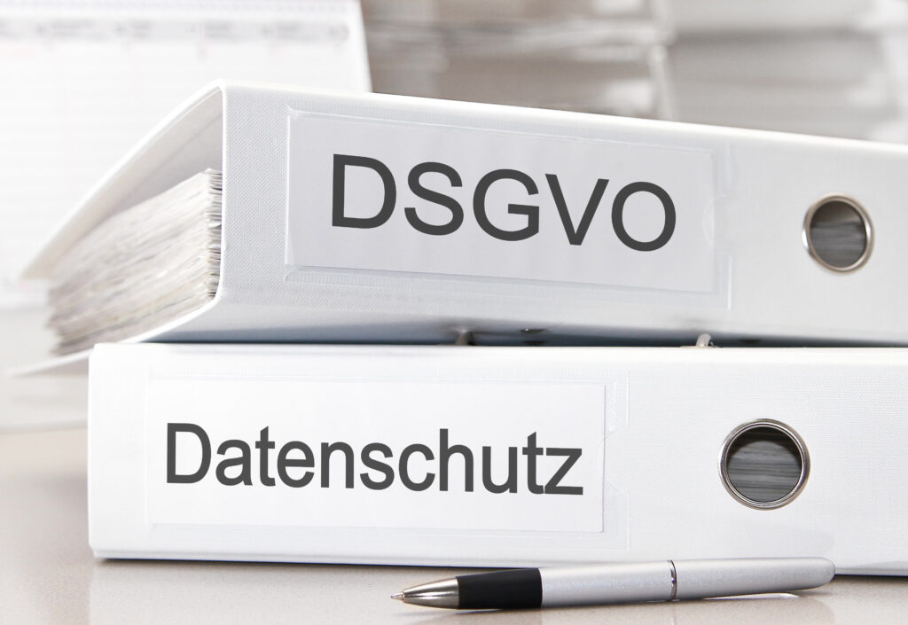 Ordner mit den Beschriftungen „DSGVO“ und „Datenschutz“ auf einem Schreibtisch.